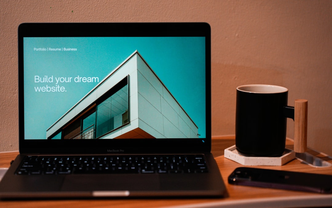 heros-img Build your dream website for your future. A laptop, MacBook, on top of a portable table with coffee tea mug on the side.